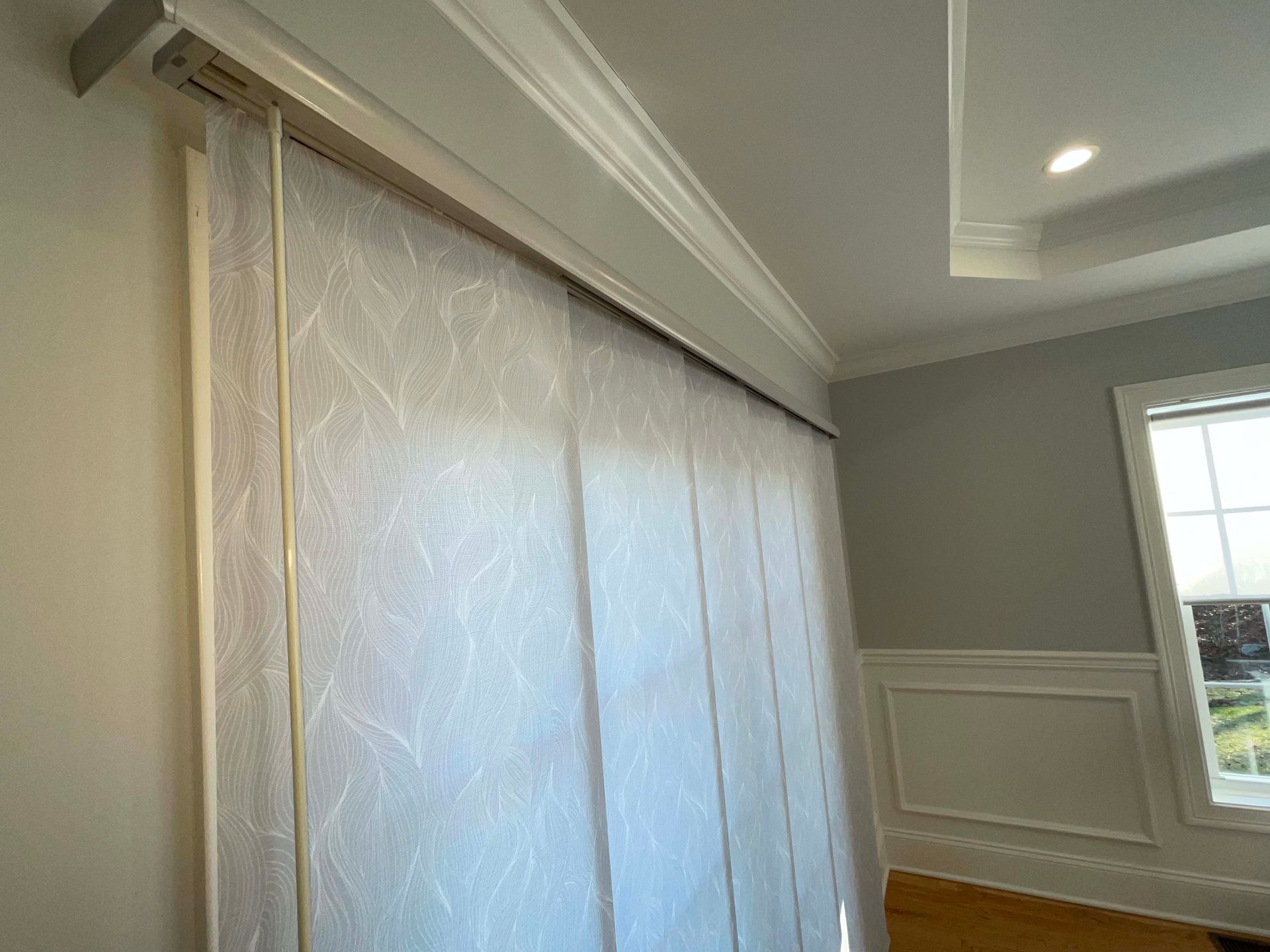 A white blind is hanging on a wall in a room next to a window.