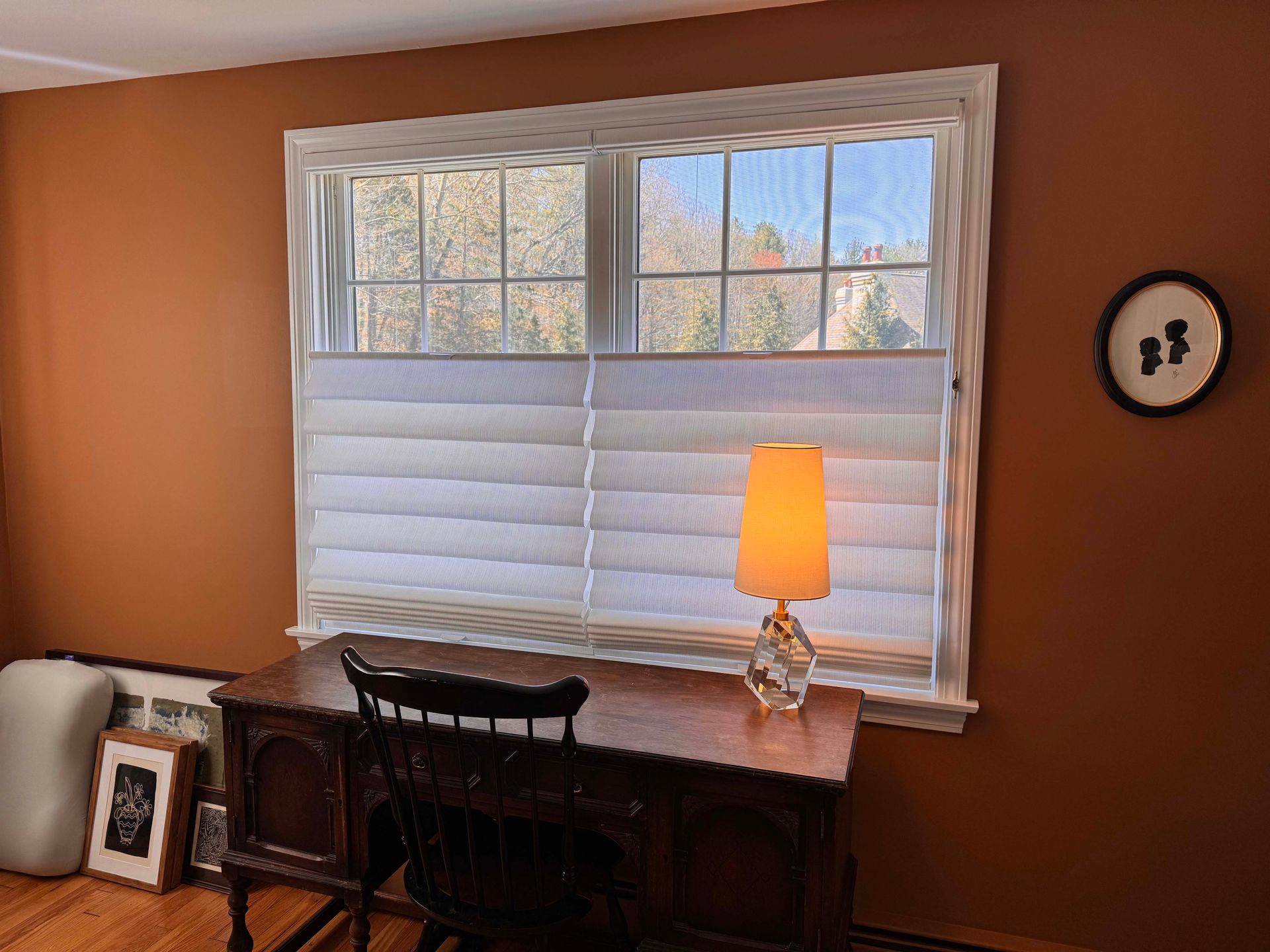 A room with a desk and a lamp in front of a window.