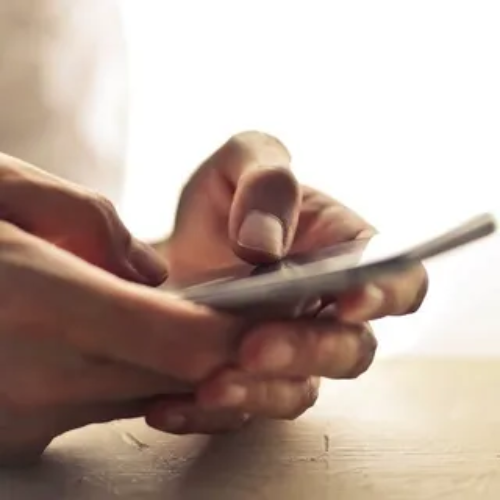 A person is holding a cell phone in their hands.