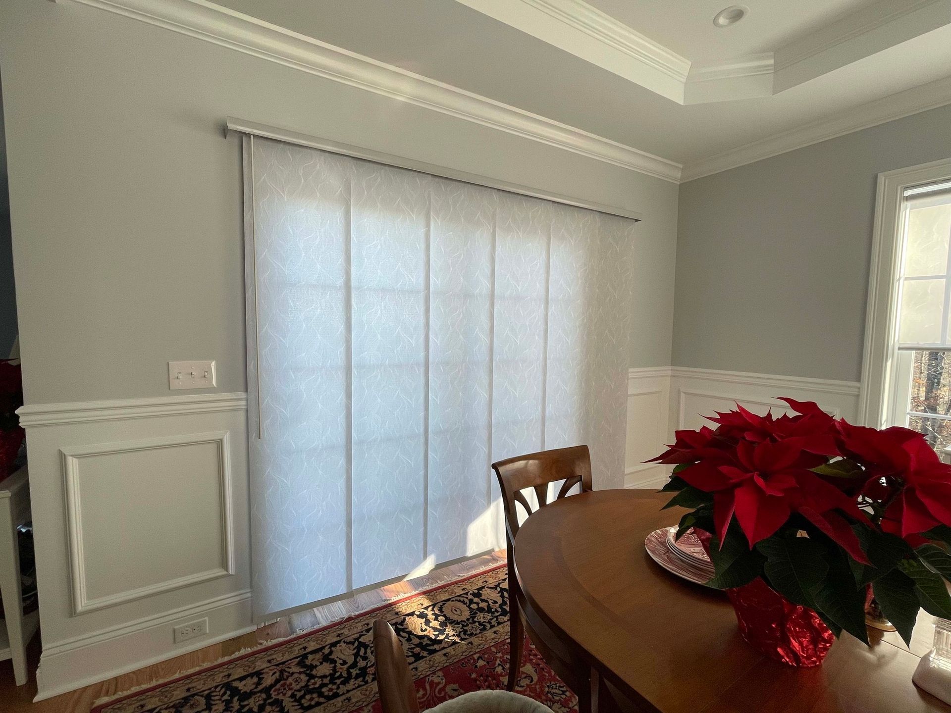 A dining room with a table and chairs and a vase of flowers.