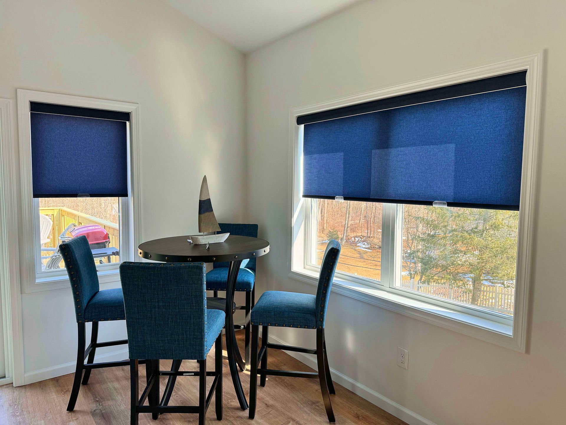 A dining room with a table and chairs and blue blinds.