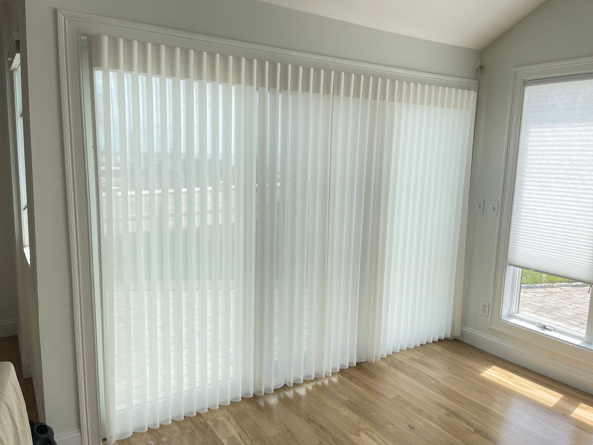 A living room with sliding glass doors and white vertical blinds.