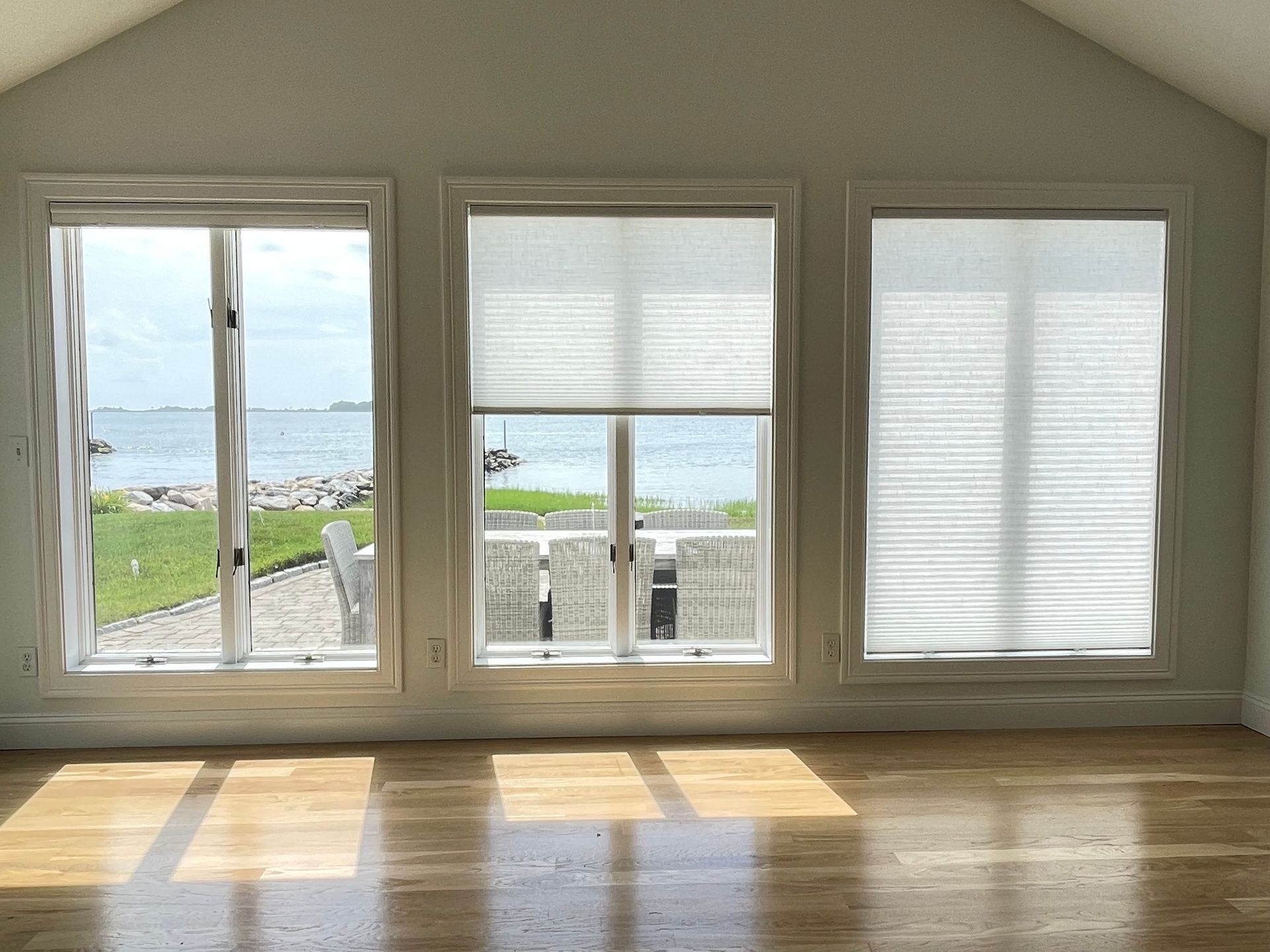 An empty room with three windows and a view of the ocean