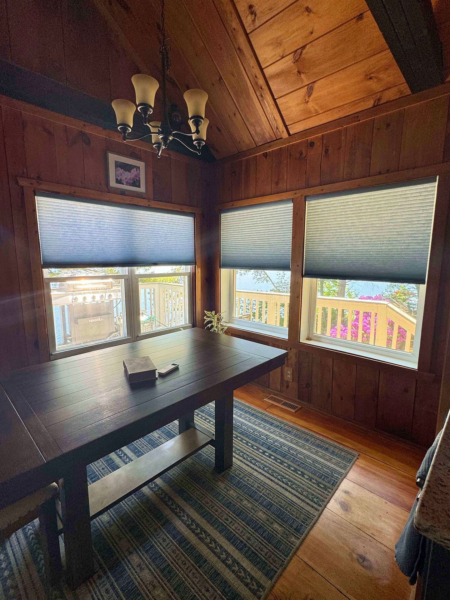 A dining room with a table and chairs and lots of windows.