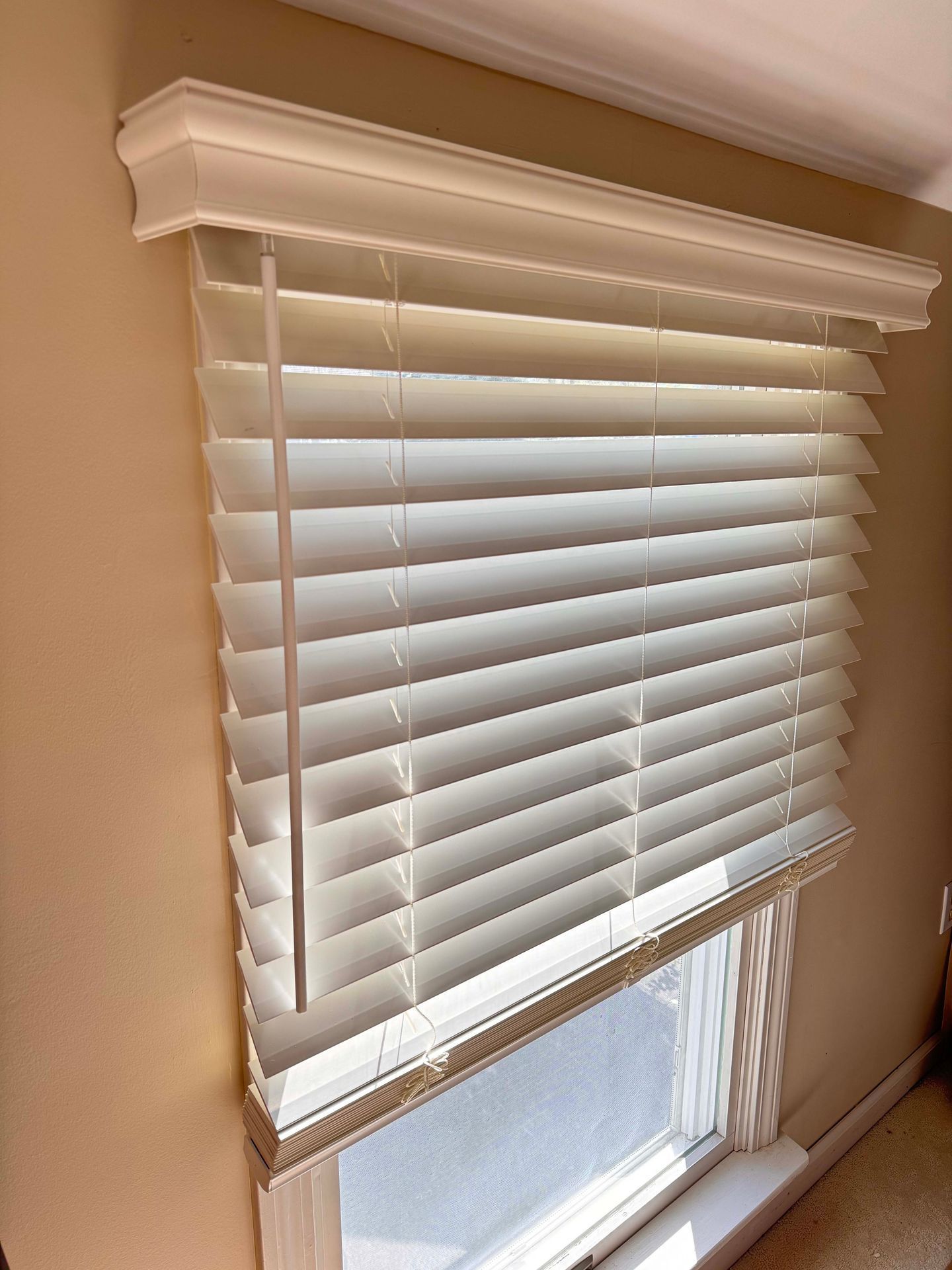 A white blind is hanging on a window in a room.