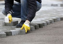 a man laying paving bricks on the ground