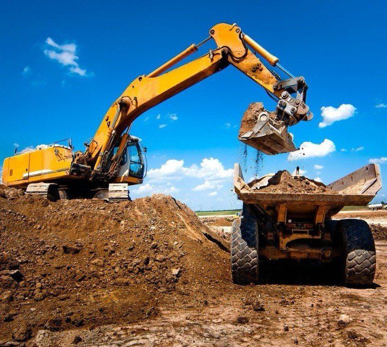 An excavator is loading dirt into a dump truck .