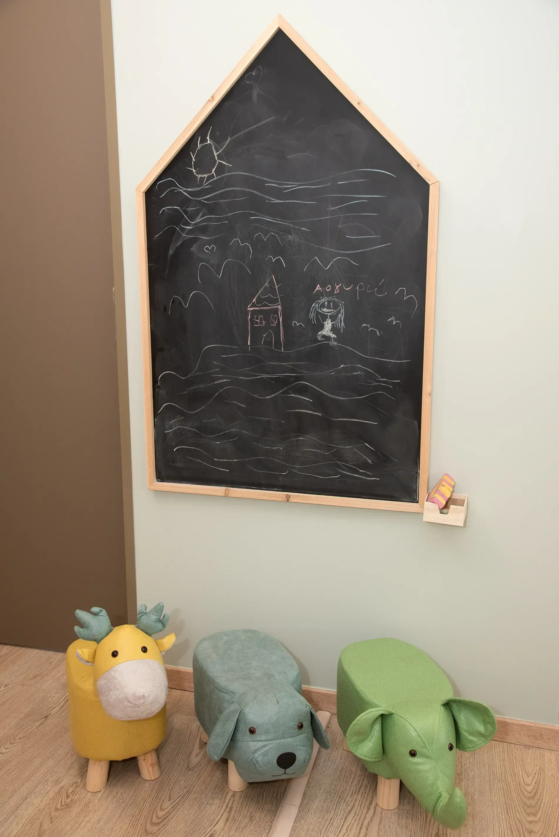 Τρία λούτρινα ζωάκια κάθονται δίπλα σε έναν πίνακα κιμωλίας σε ένα δωμάτιο.