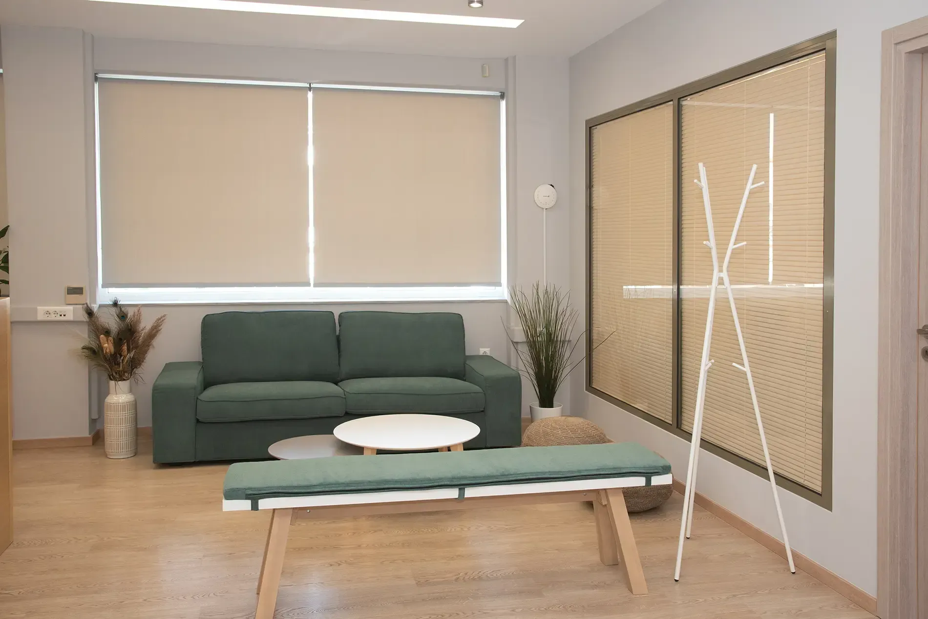 Ένα σαλόνι με καναπέ, τραπέζι, πάγκο και παράθυρο.