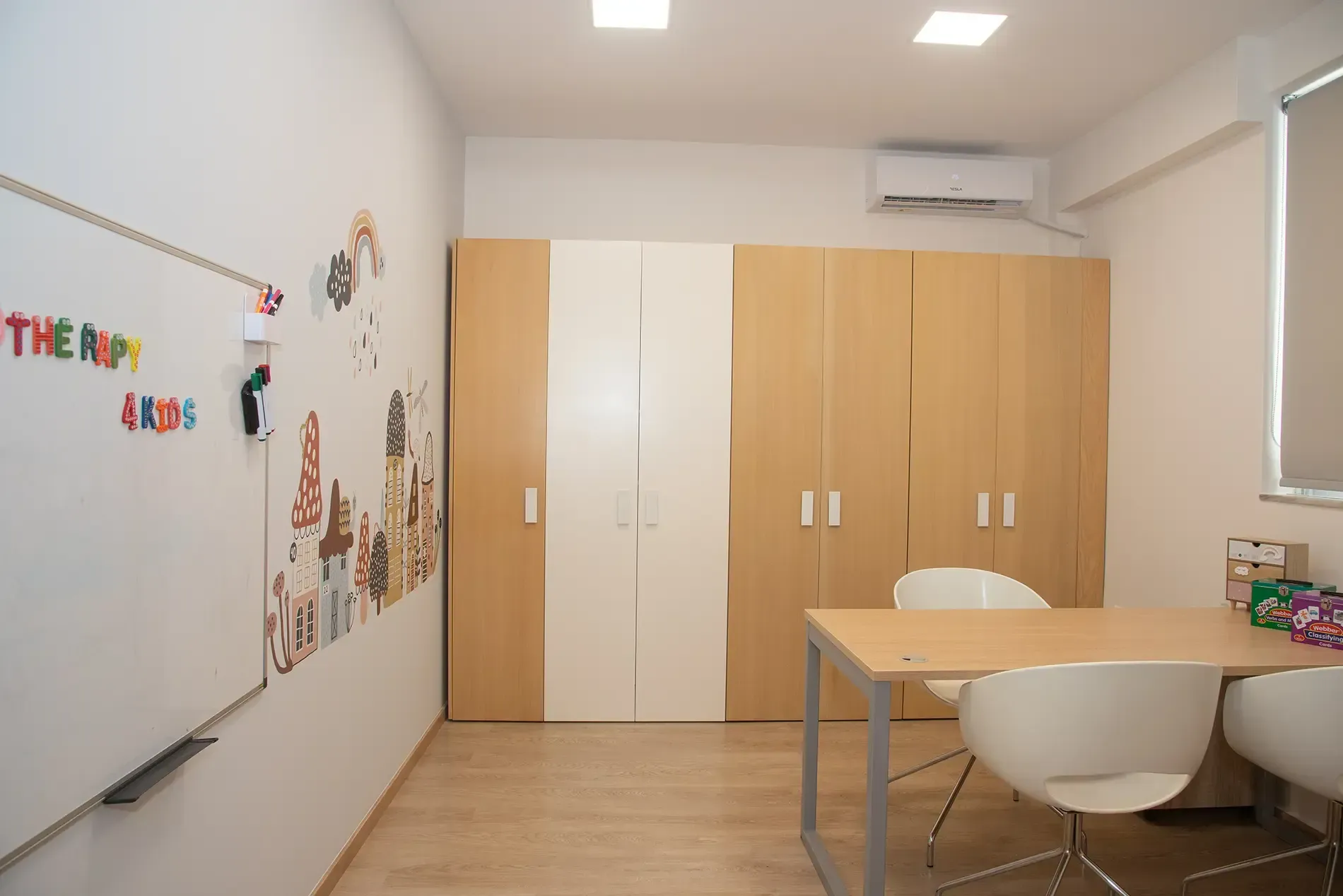 Ένα δωμάτιο με τραπέζι και καρέκλες και έναν πίνακα που λέει χώρους θεραπείας.