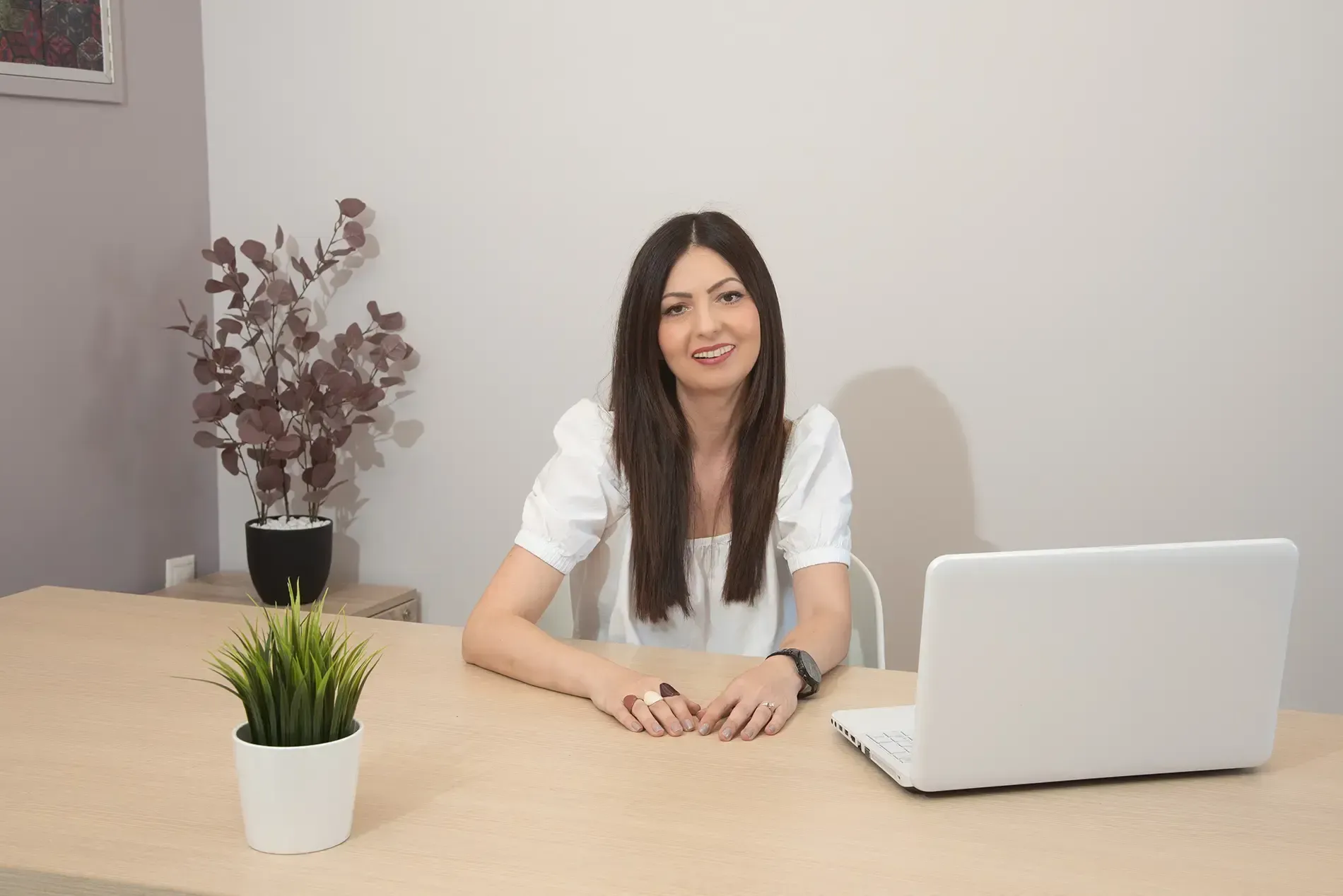 Μια γυναίκα κάθεται σε ένα γραφείο μπροστά από έναν φορητό υπολογιστή.