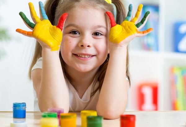 Χαμογελαστό κορίτσι με βαμμένα χέρια που παίζει με χρώματα – Παιδιατρική εργοθεραπεία και ανάπτυξη.