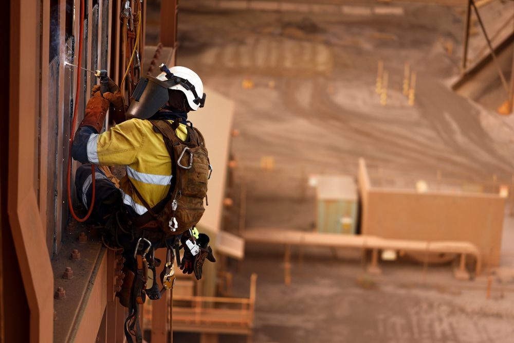 Man Wearing A Helmet And Safety Gear While Welding A Building — Height Safety in Cairns, QLD