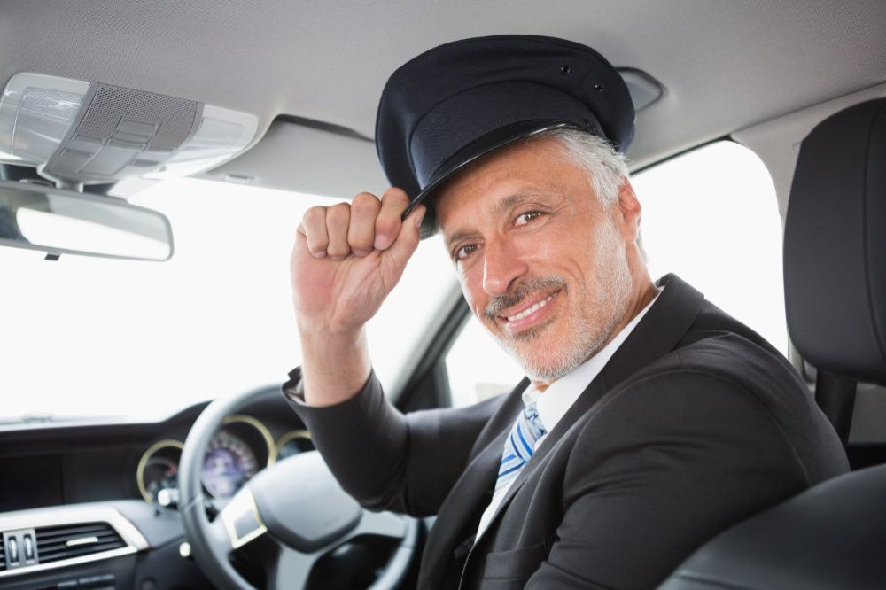 A man in a suit and tie is sitting in the driver 's seat of a car.