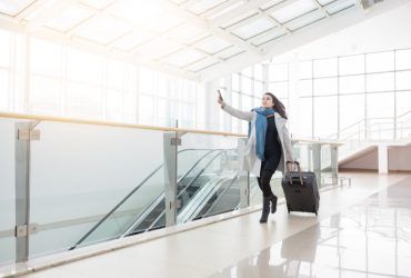 A woman is walking with a suitcase in an airport.