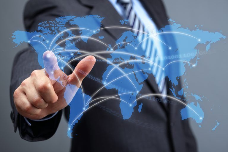 A man in a suit and tie is pointing at a map of the world.