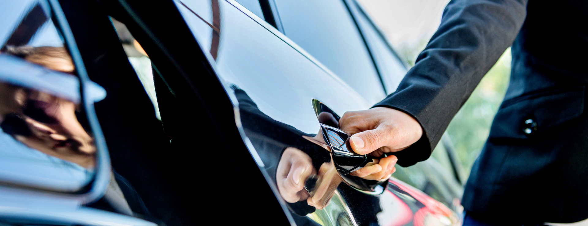 A person in a suit opening a car door.