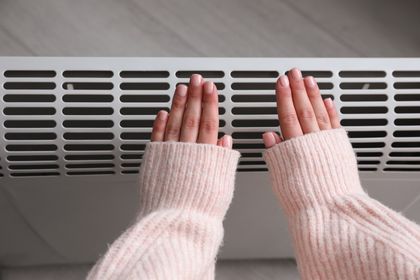 Woman Warming Hands Near Electric Heater — Freehold, NJ — Teplo Design Heating and Air Conditioning