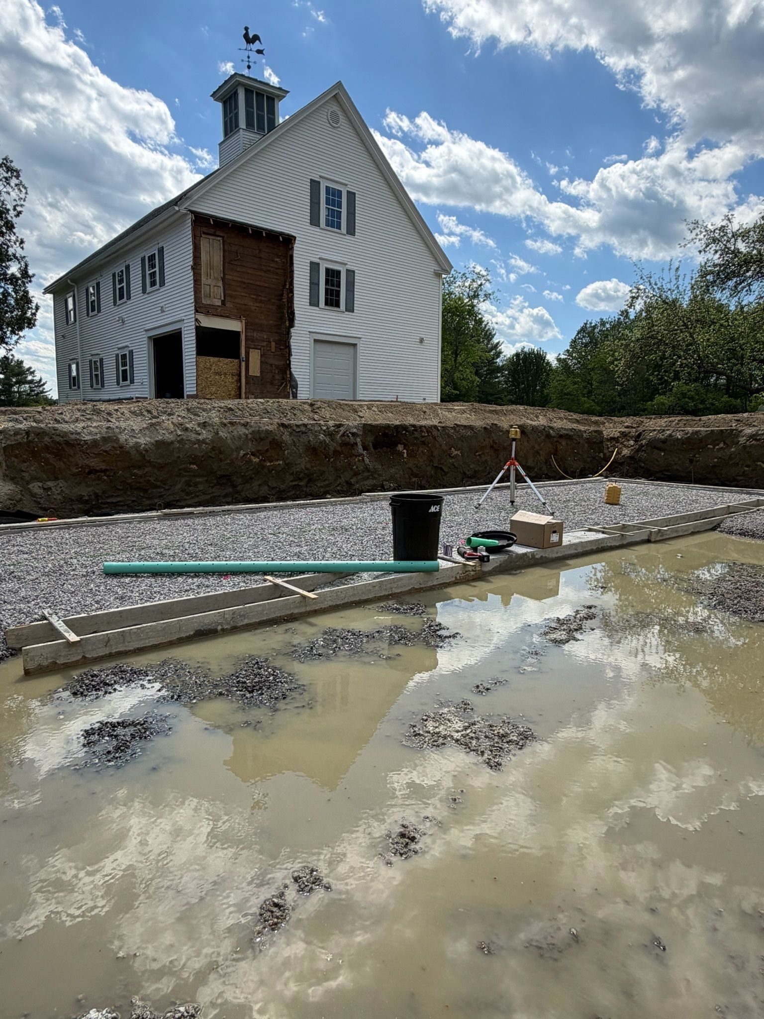 White lighthouse on a rocky shore with muddy water and a cloudy sky