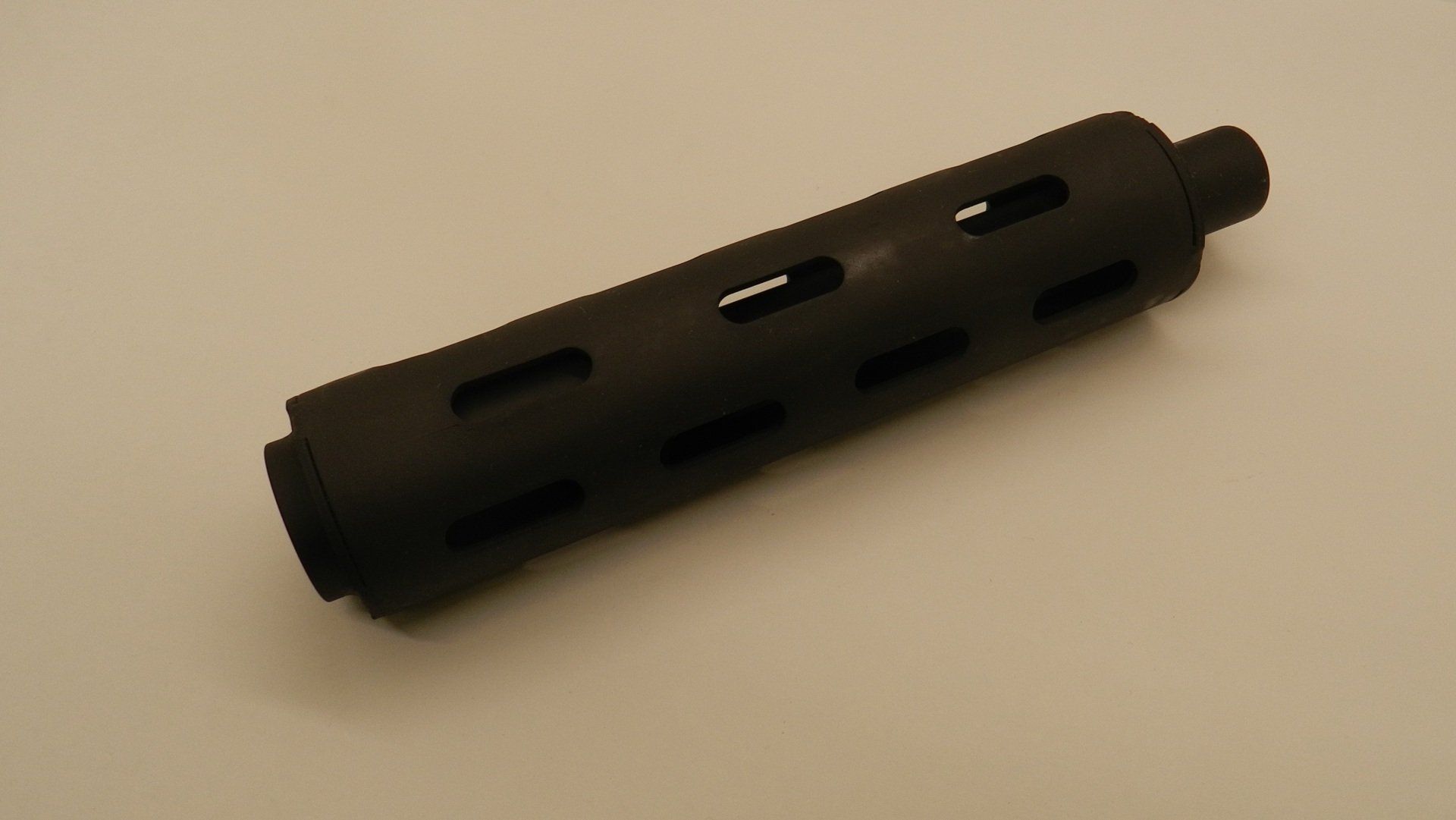 A black tube with holes in it is on a white surface