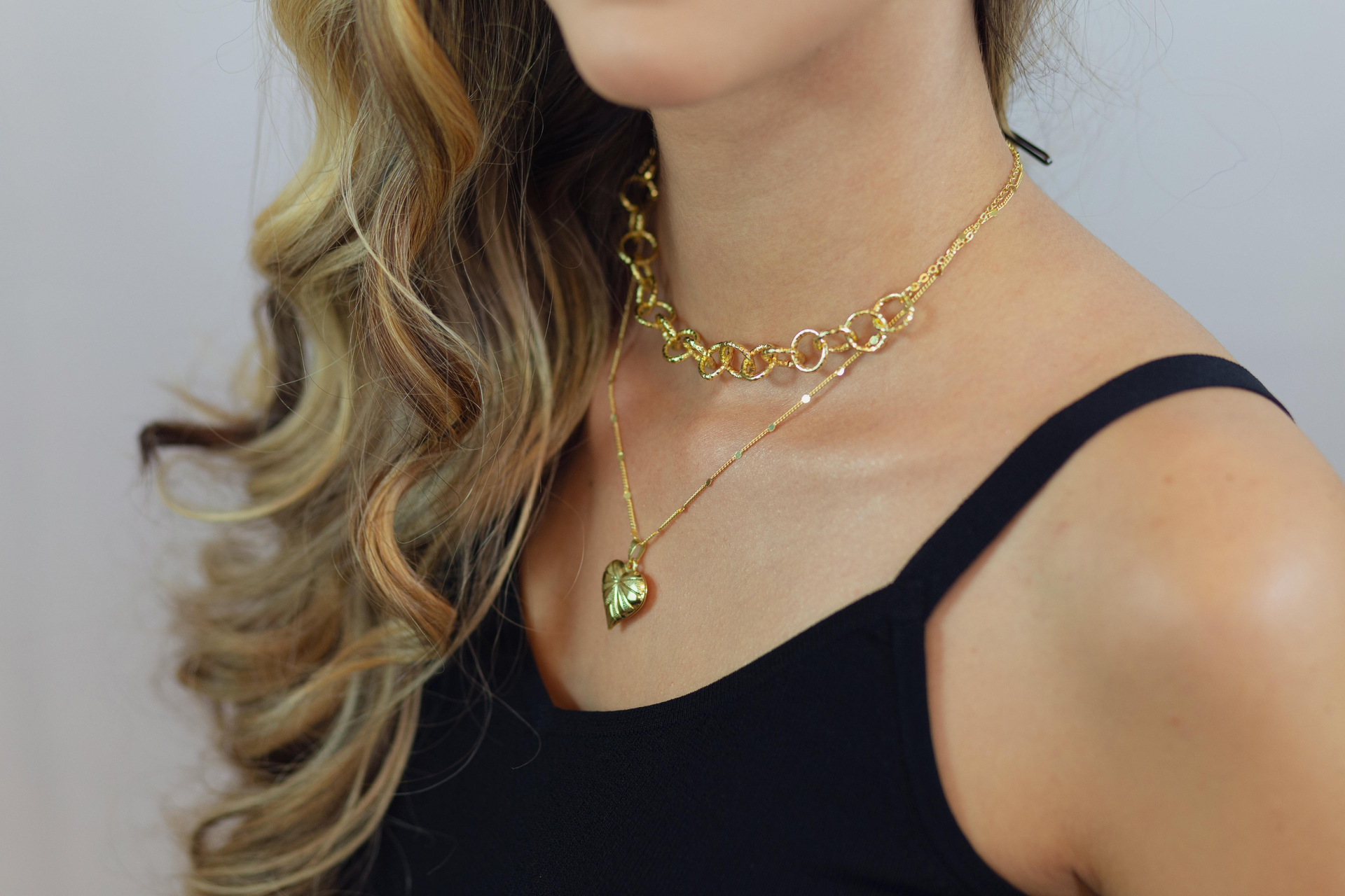 A woman is wearing a choker necklace with a heart shaped pendant.