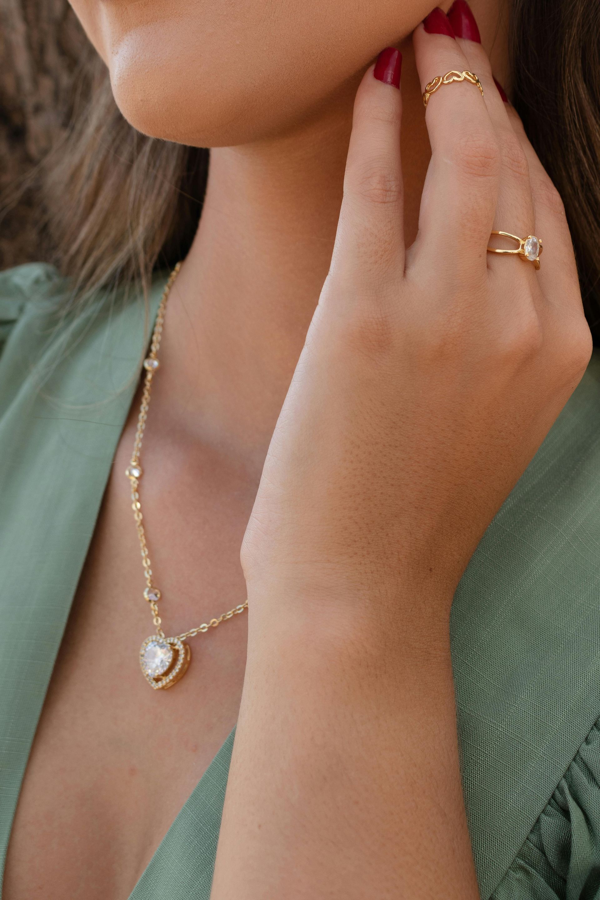 A woman wearing a necklace and a ring on her finger.