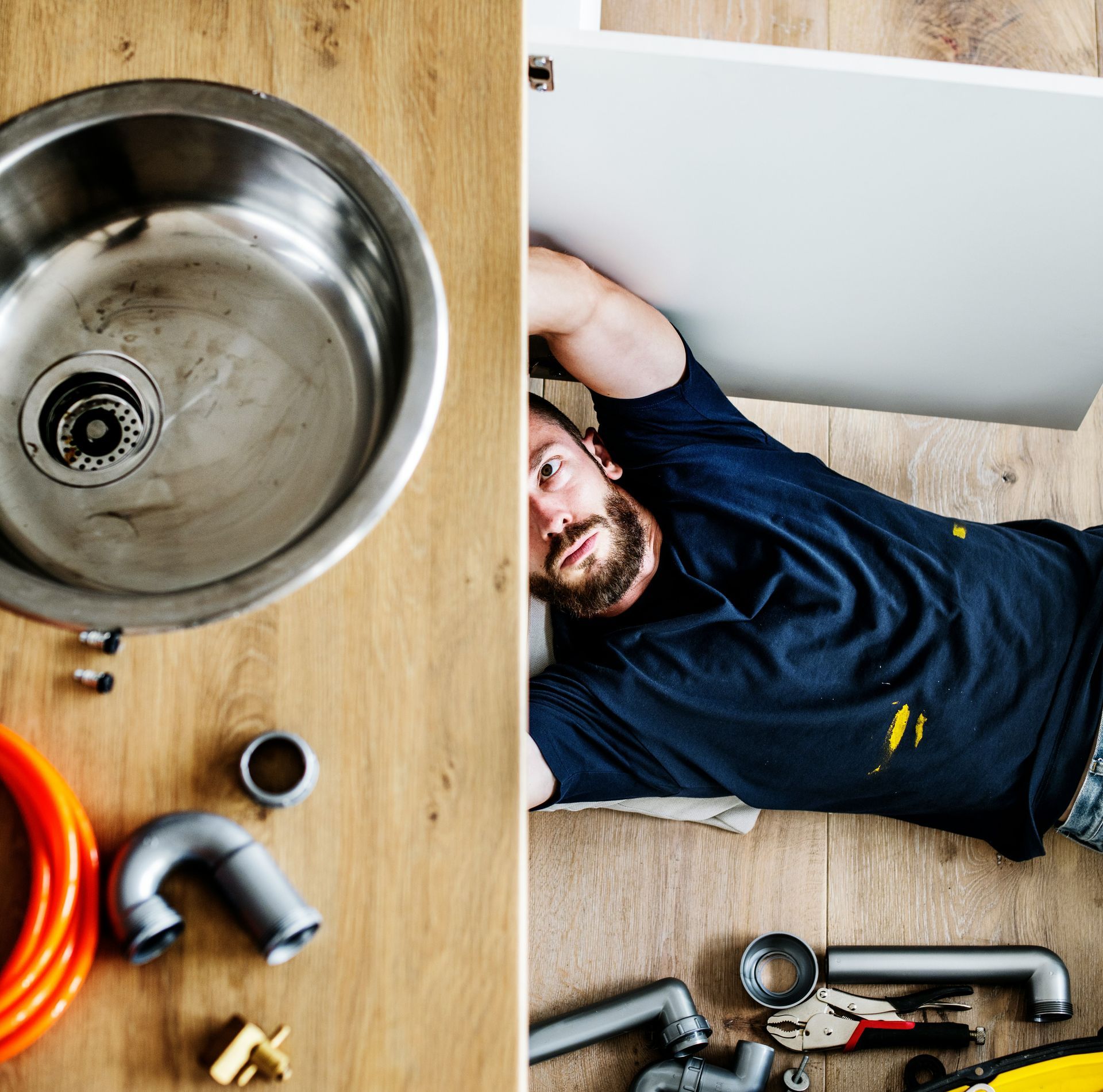 A man is laying on the floor next to a sink