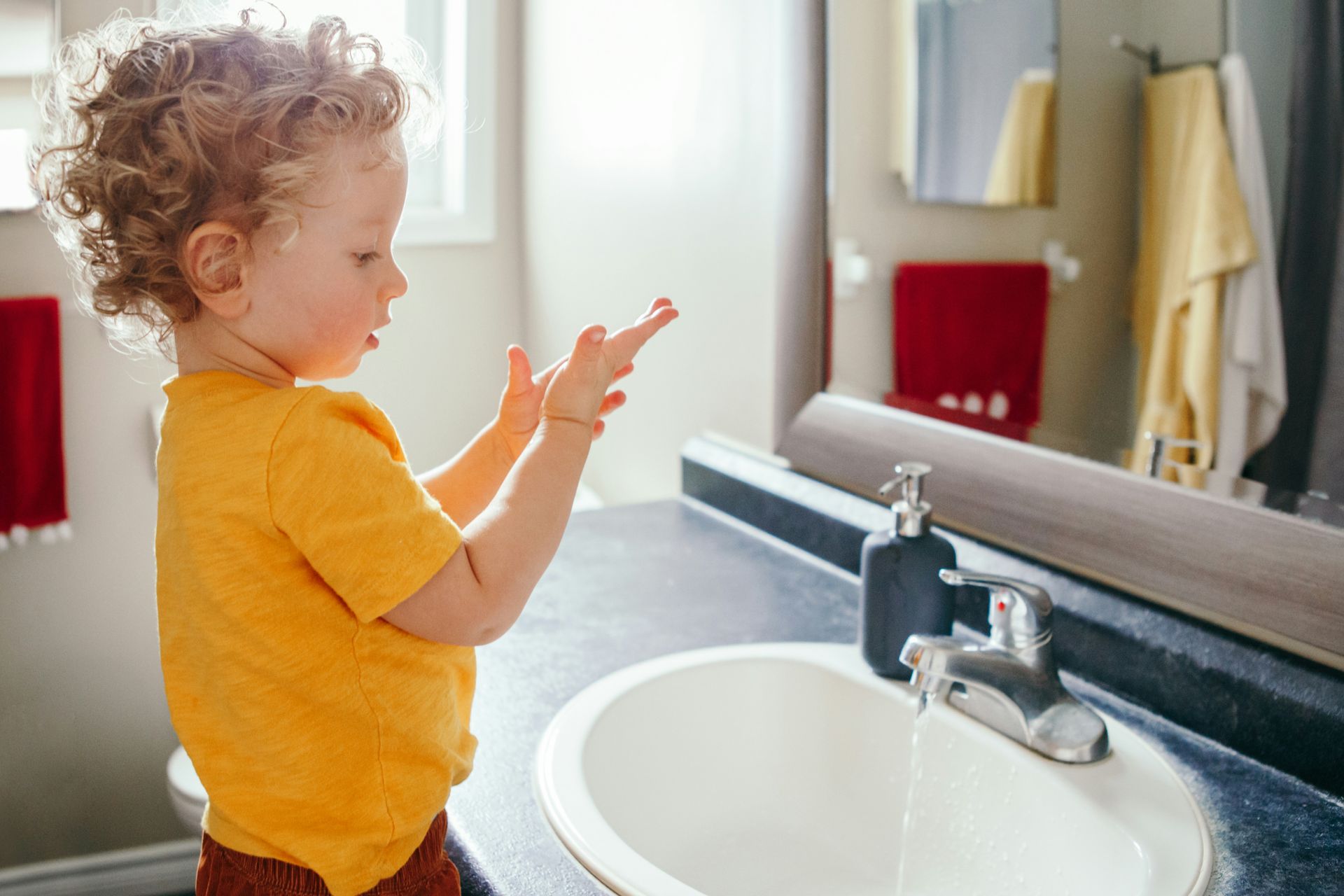 A young boy is washing his hands in a bathroom sink.