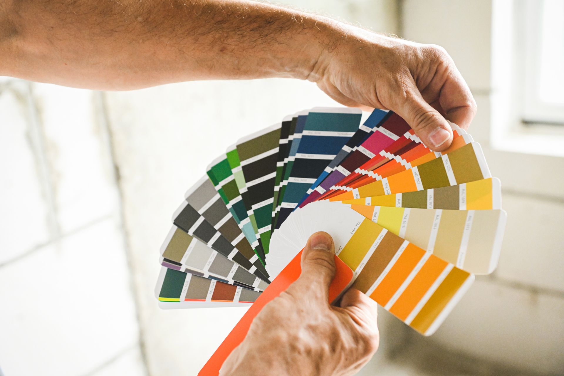 A person is holding a fan of paint samples in their hands.