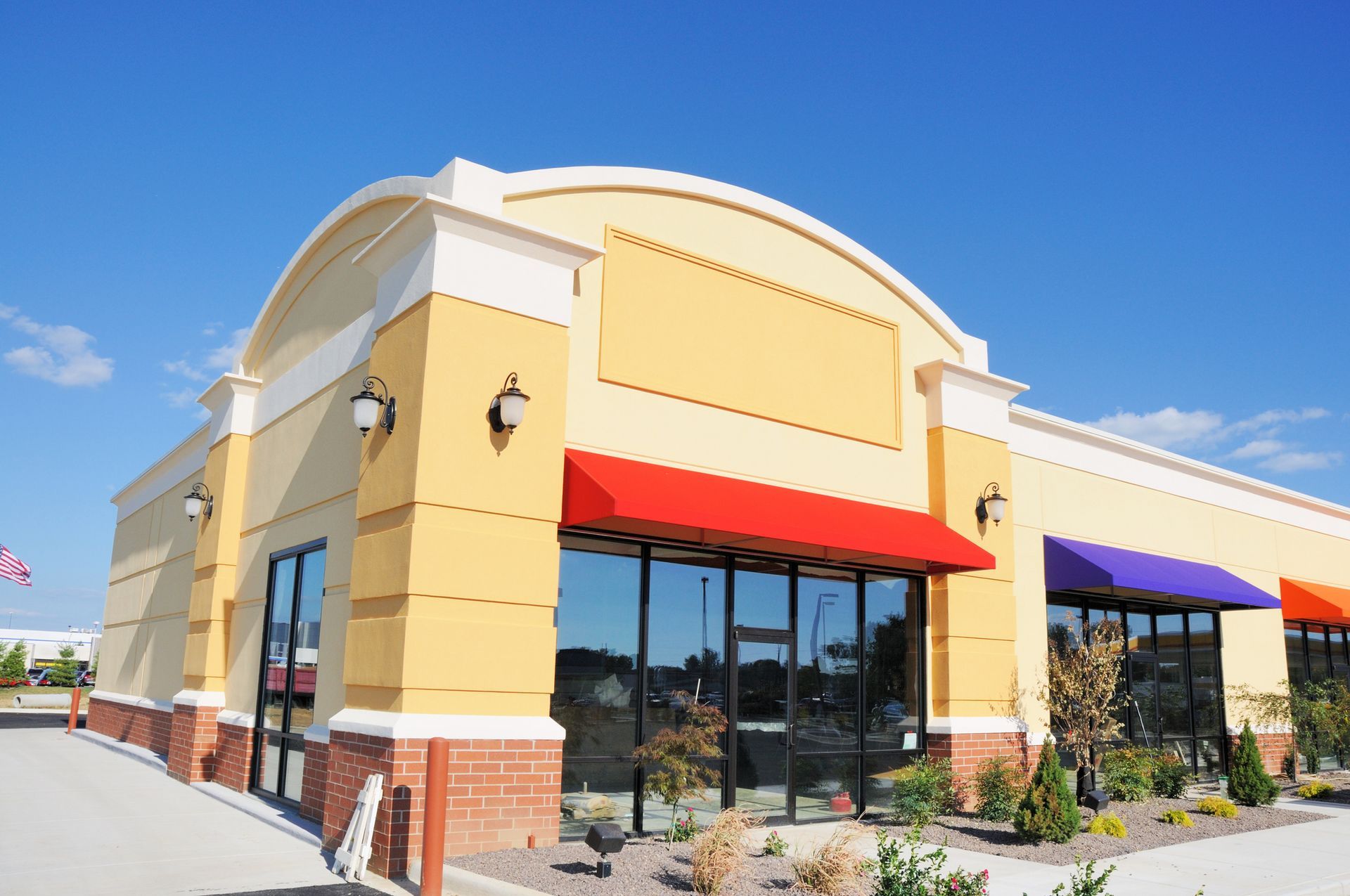 A yellow building with red and purple awnings on the windows