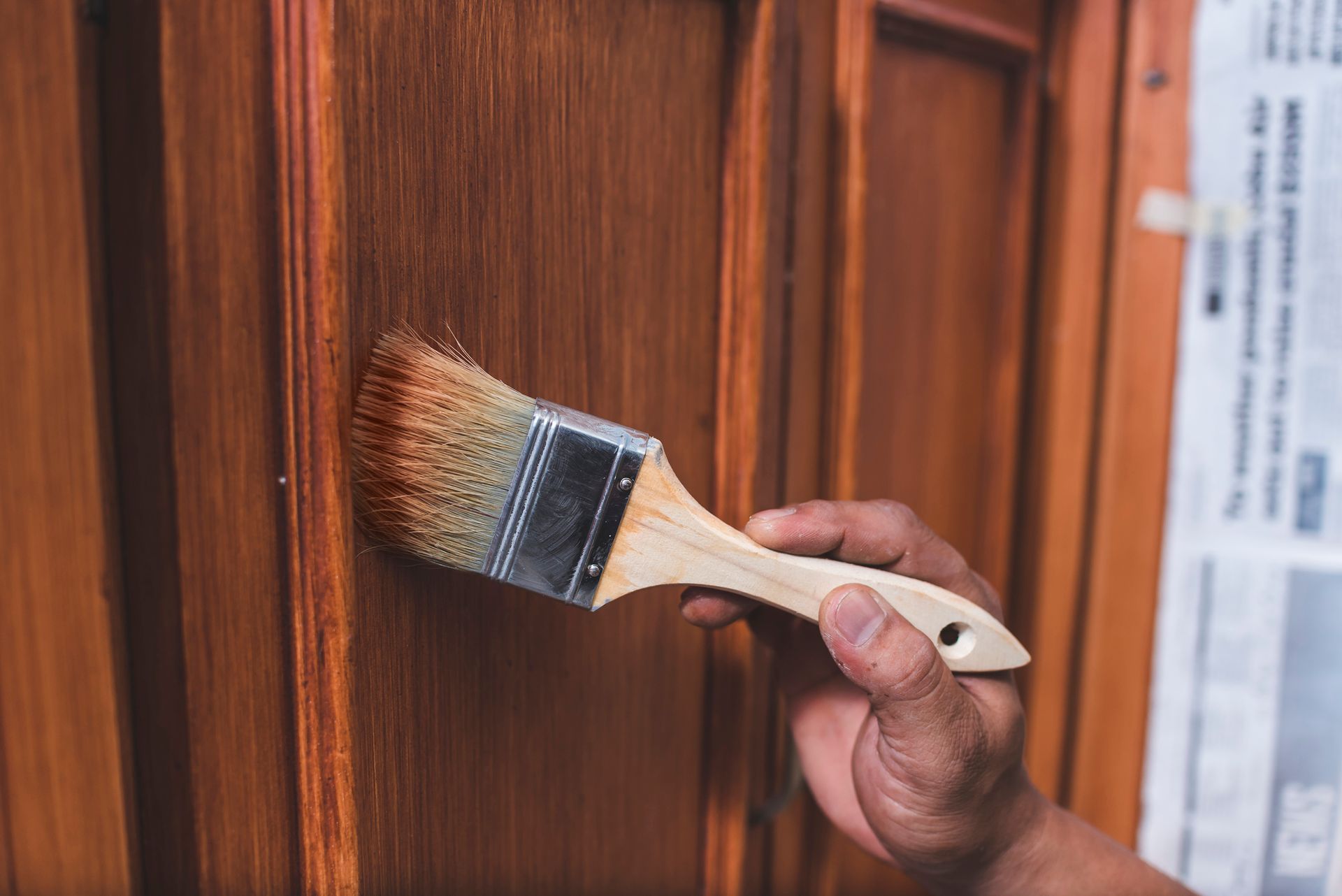 A person is painting a wooden door with a brush.