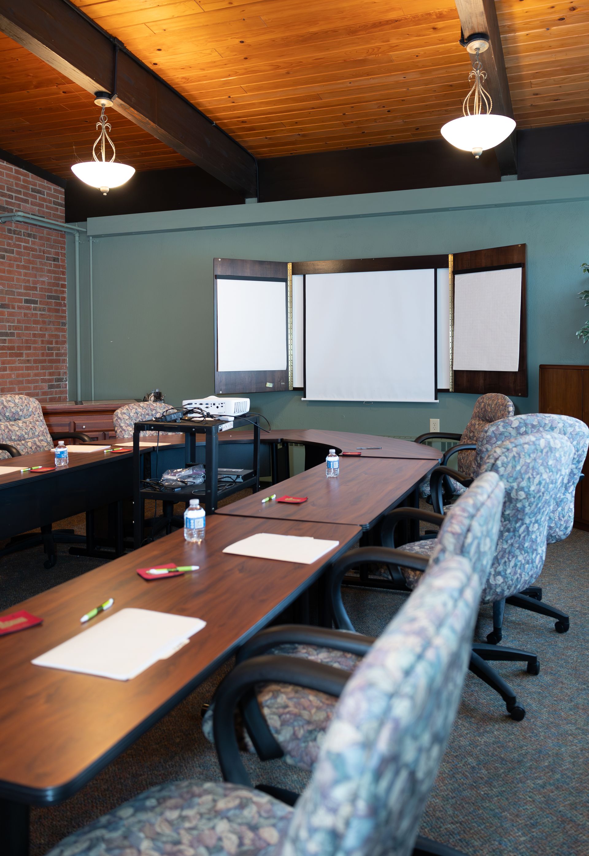 A conference room with tables and chairs and a projector screen