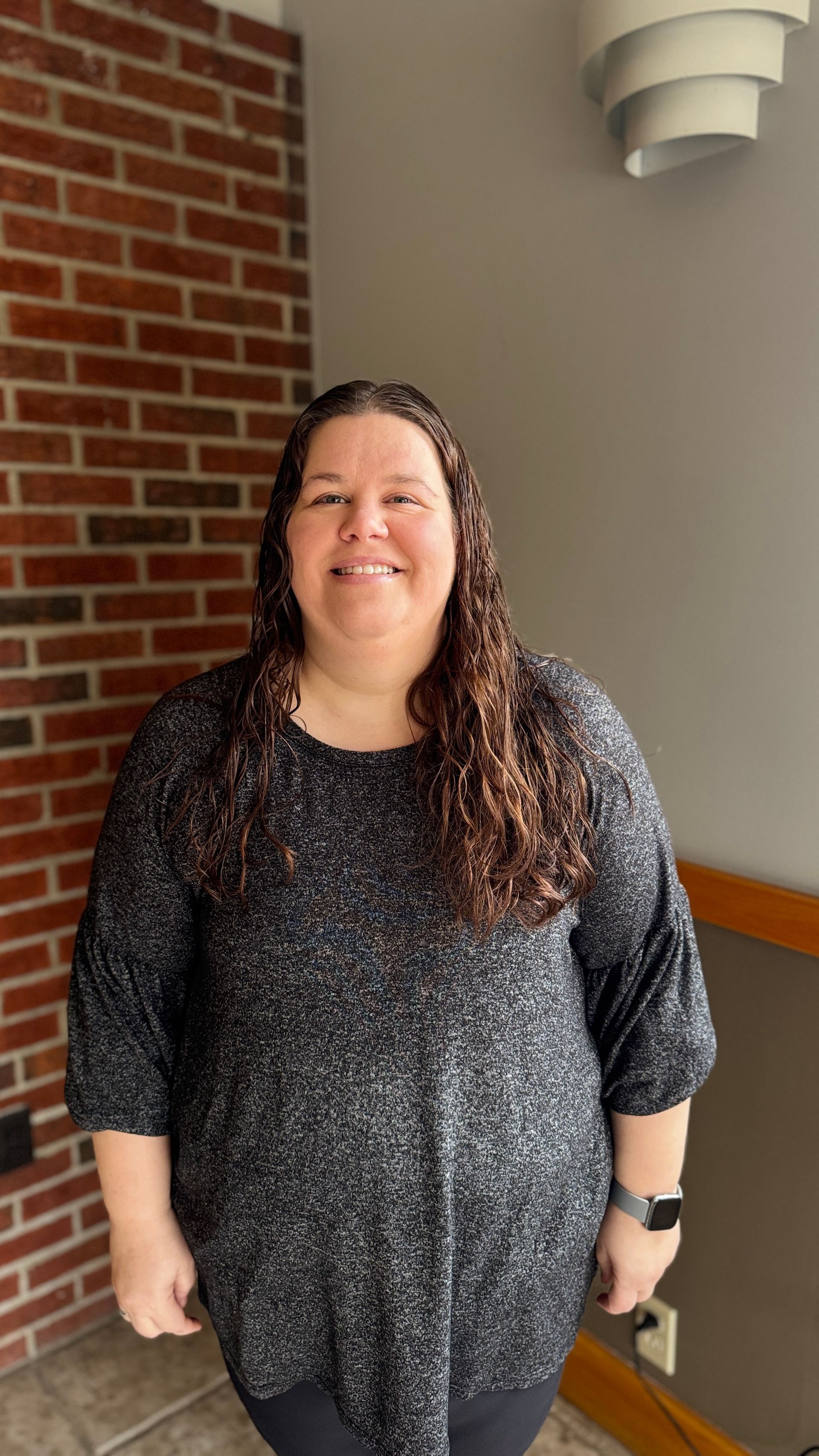 A woman in a red shirt is smiling for the camera