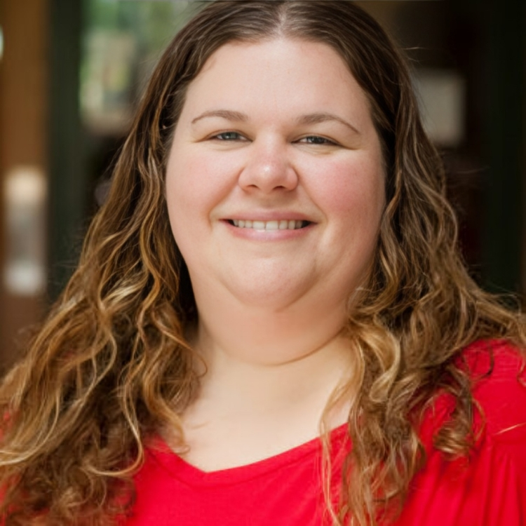 A woman in a red shirt is smiling for the camera