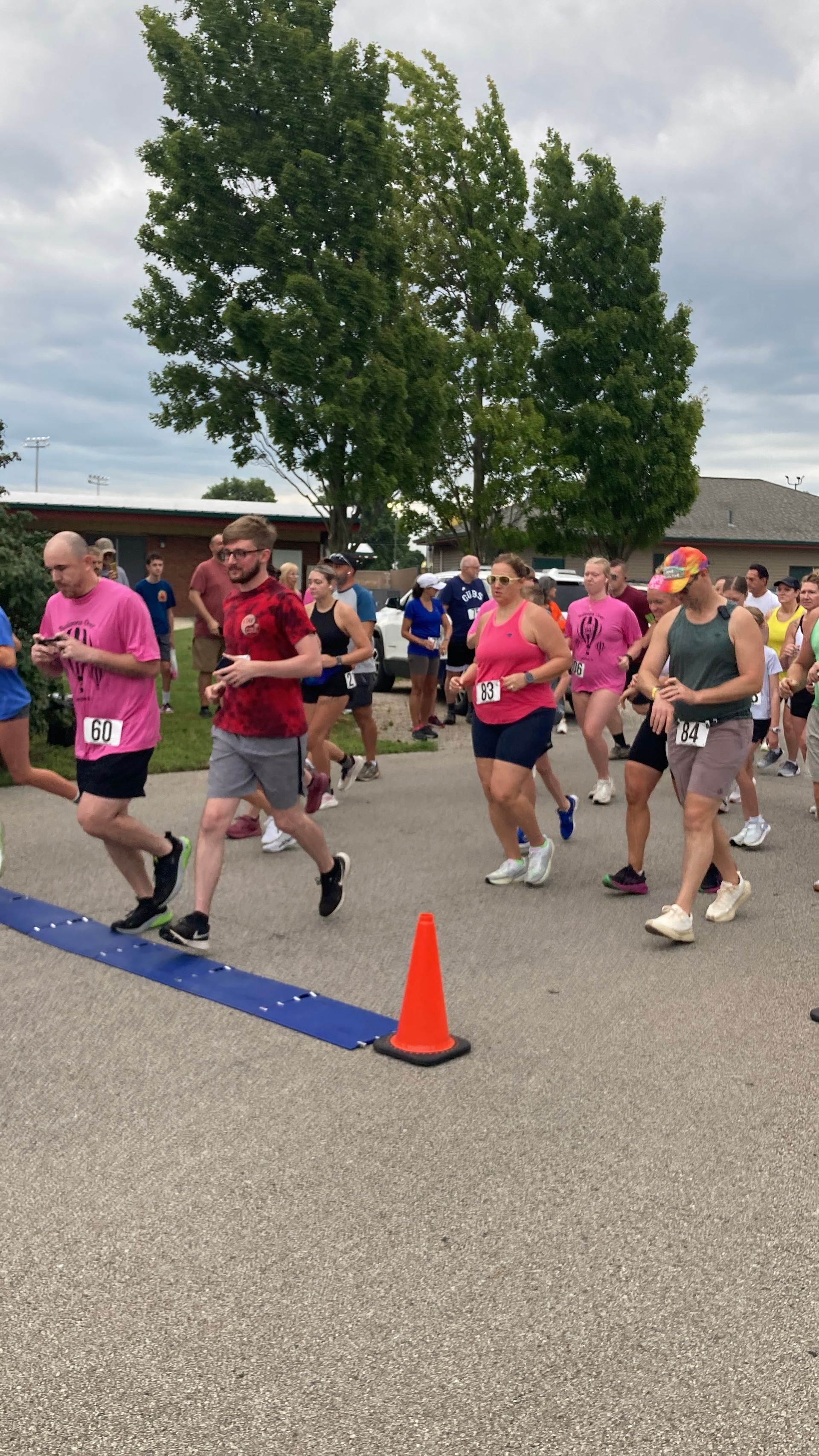 A man and a woman are posing for a picture in a parking lot.