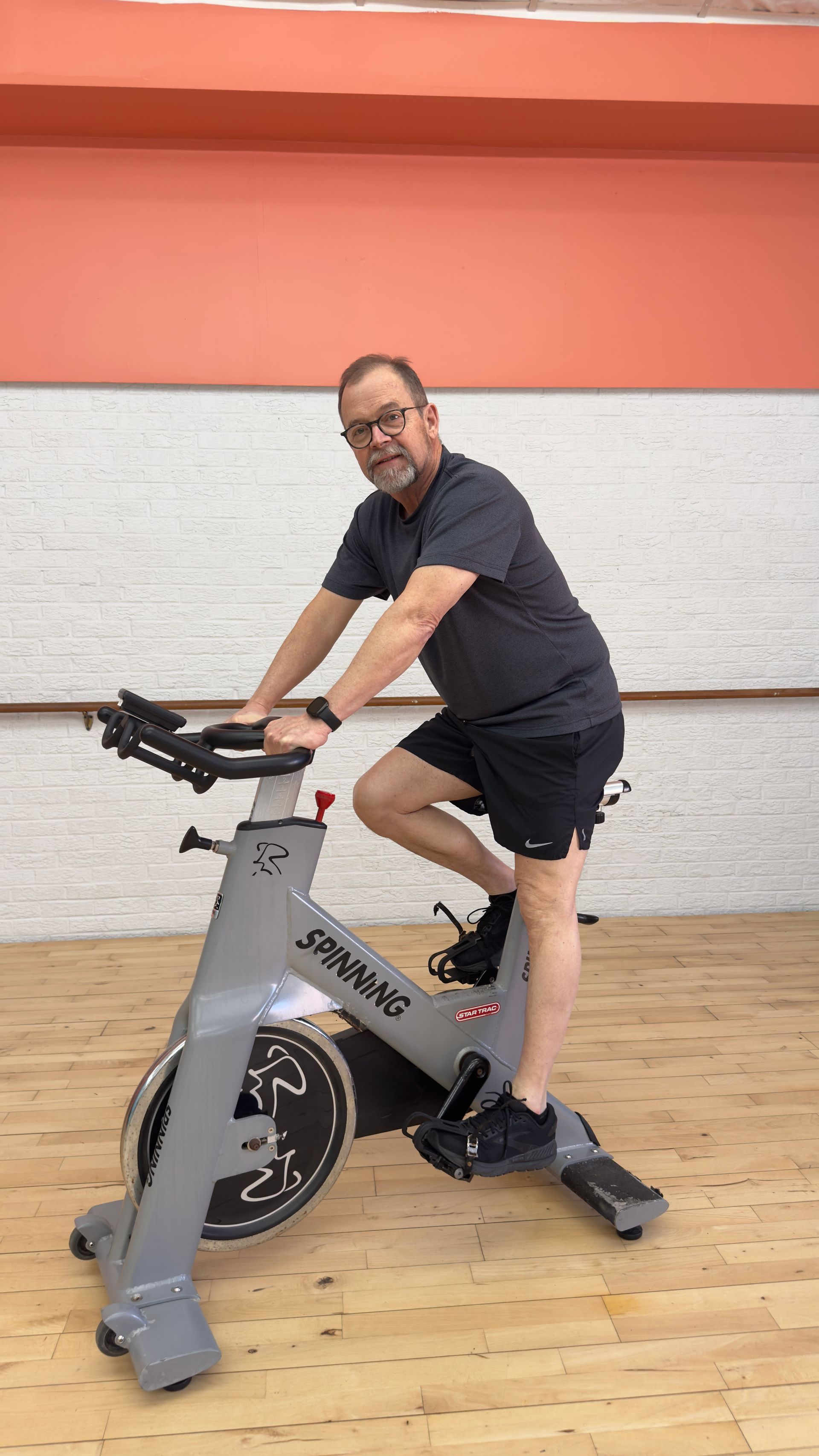 A man is riding an exercise bike in a gym.