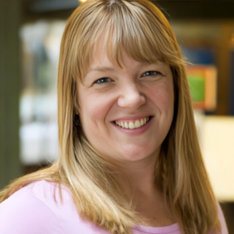 A woman in a pink shirt is smiling for the camera