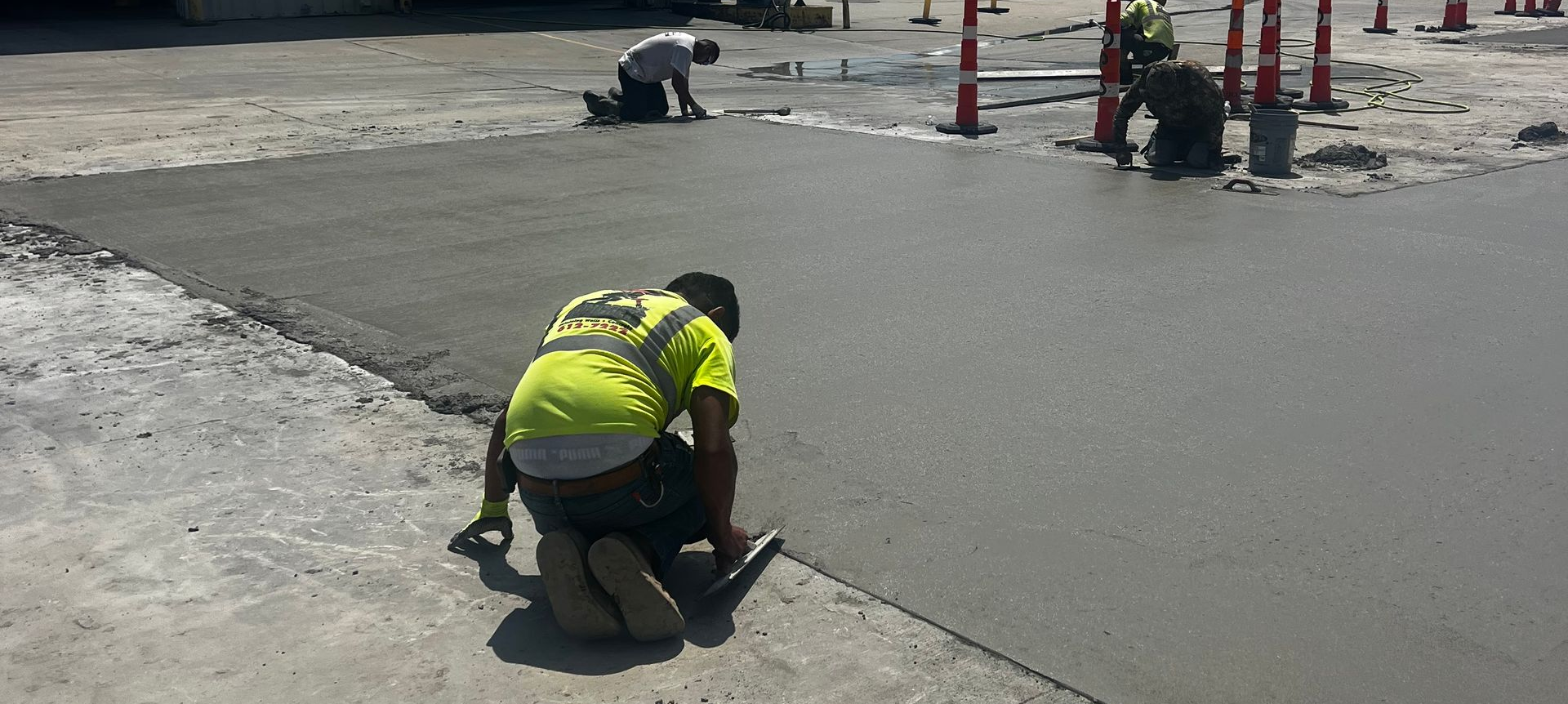 Concrete driveway contractor applying cement with a trowel.
