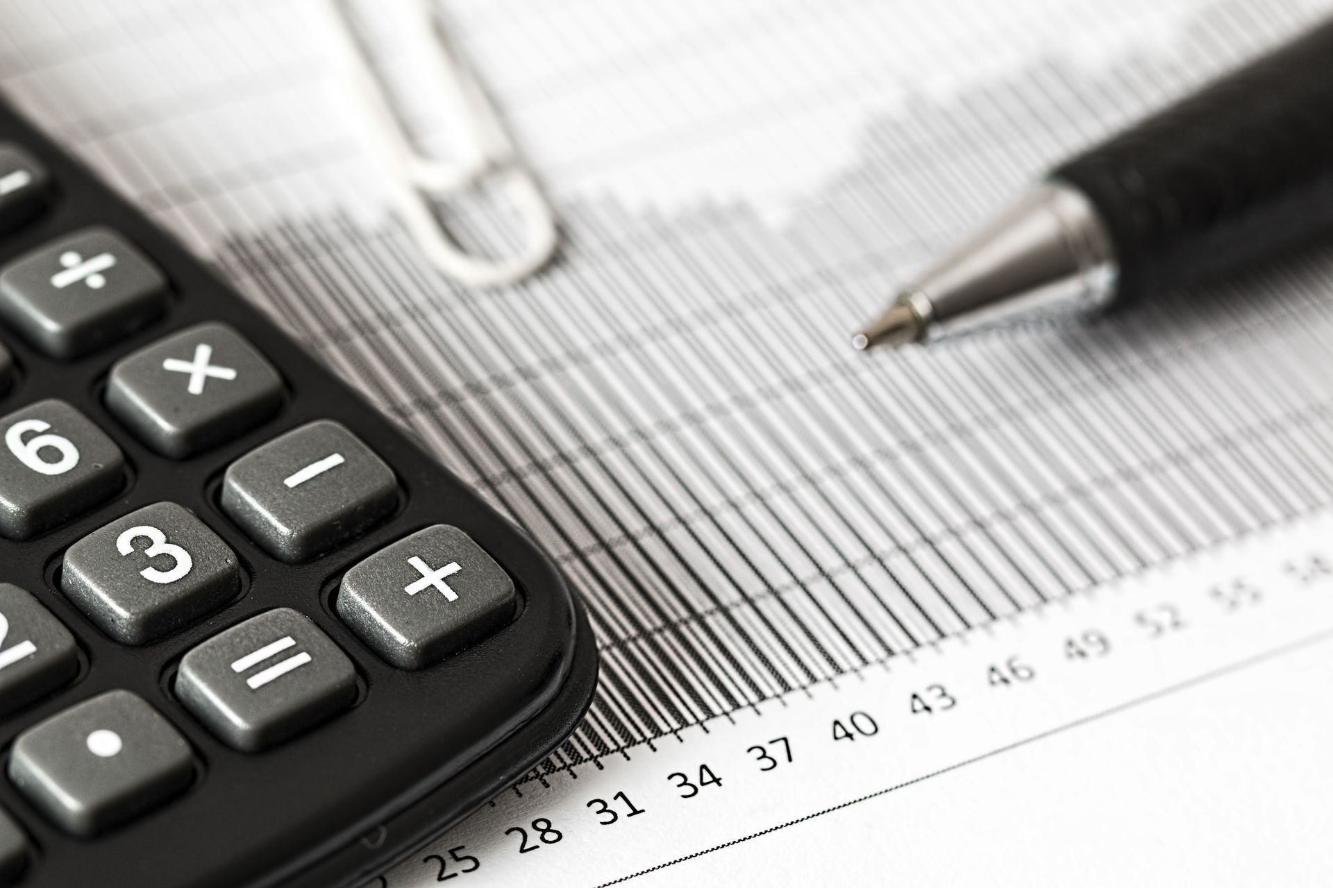 Calculator and pen on financial spreadsheet with close-up numbers