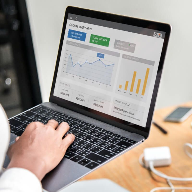 Hand using a laptop showing the QuickBooks dashboard on screen