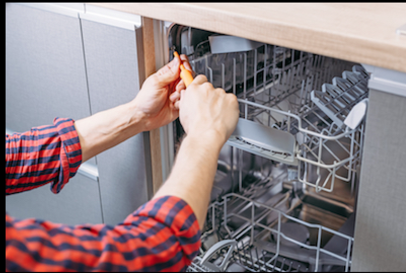 Person using a screwdriver to repair a dishwasher.