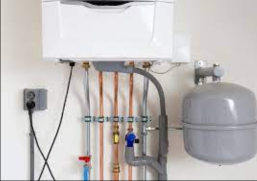 White wall-mounted boiler with copper pipes, valves, and a gray expansion tank.