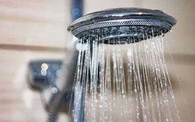 Chrome shower head with water streaming down.