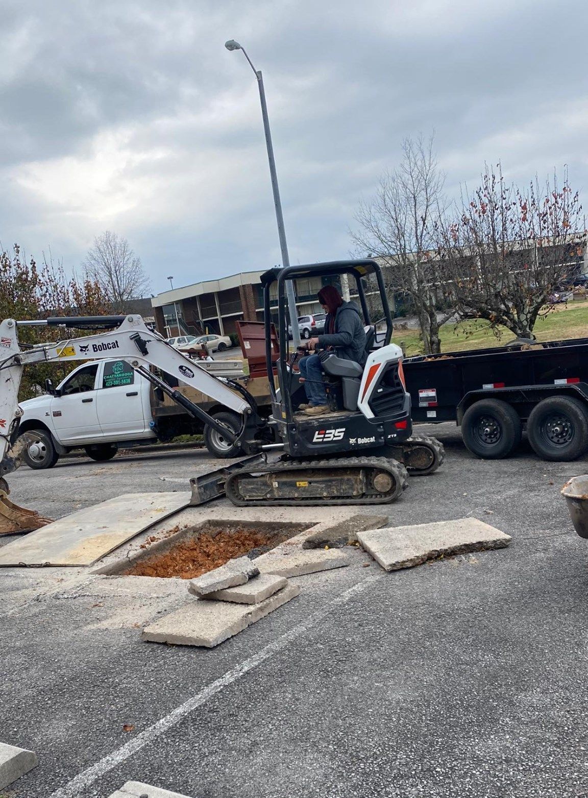 Two men are working on a manhole cover in the dirt.