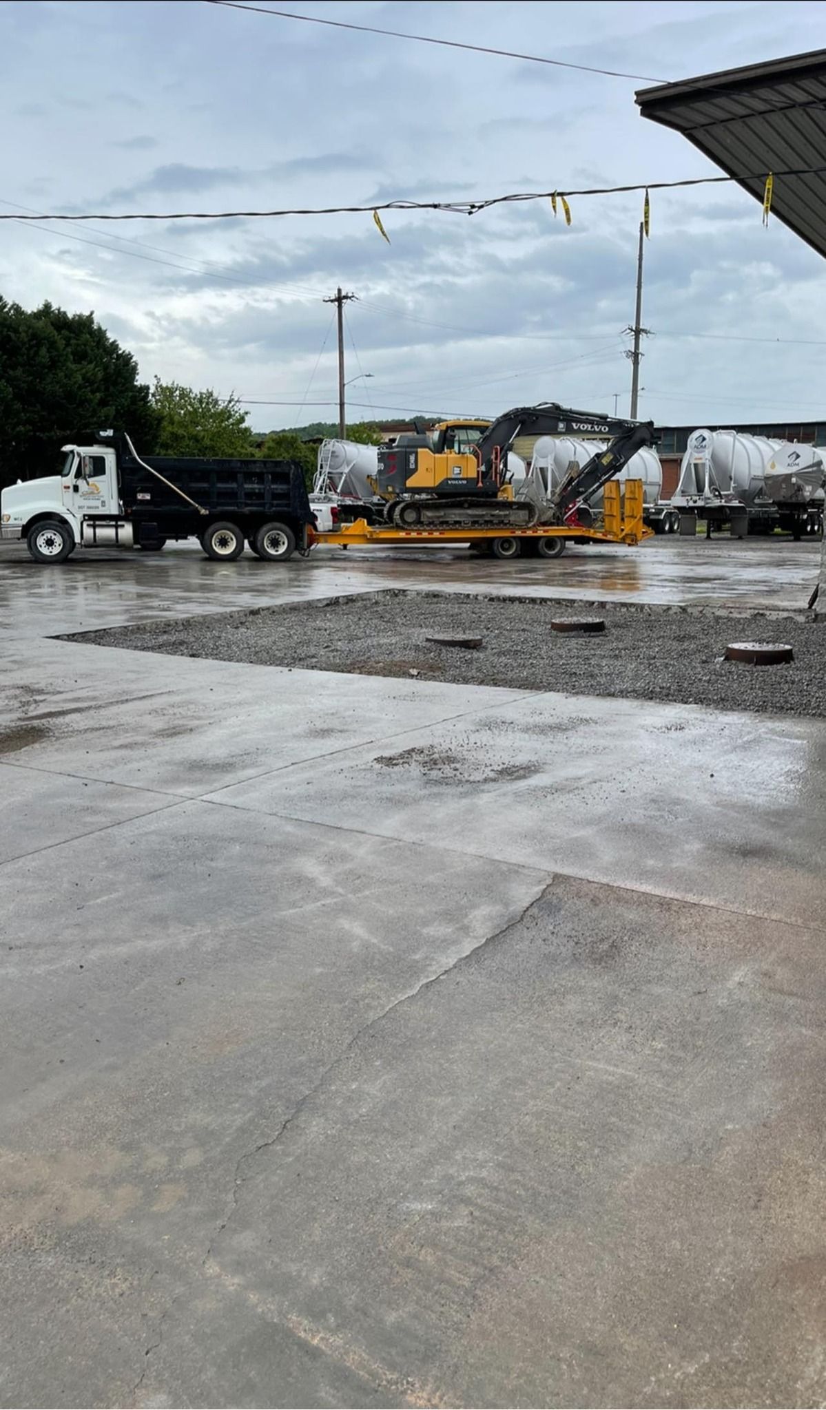 A dump truck is parked in a parking lot next to a bulldozer.