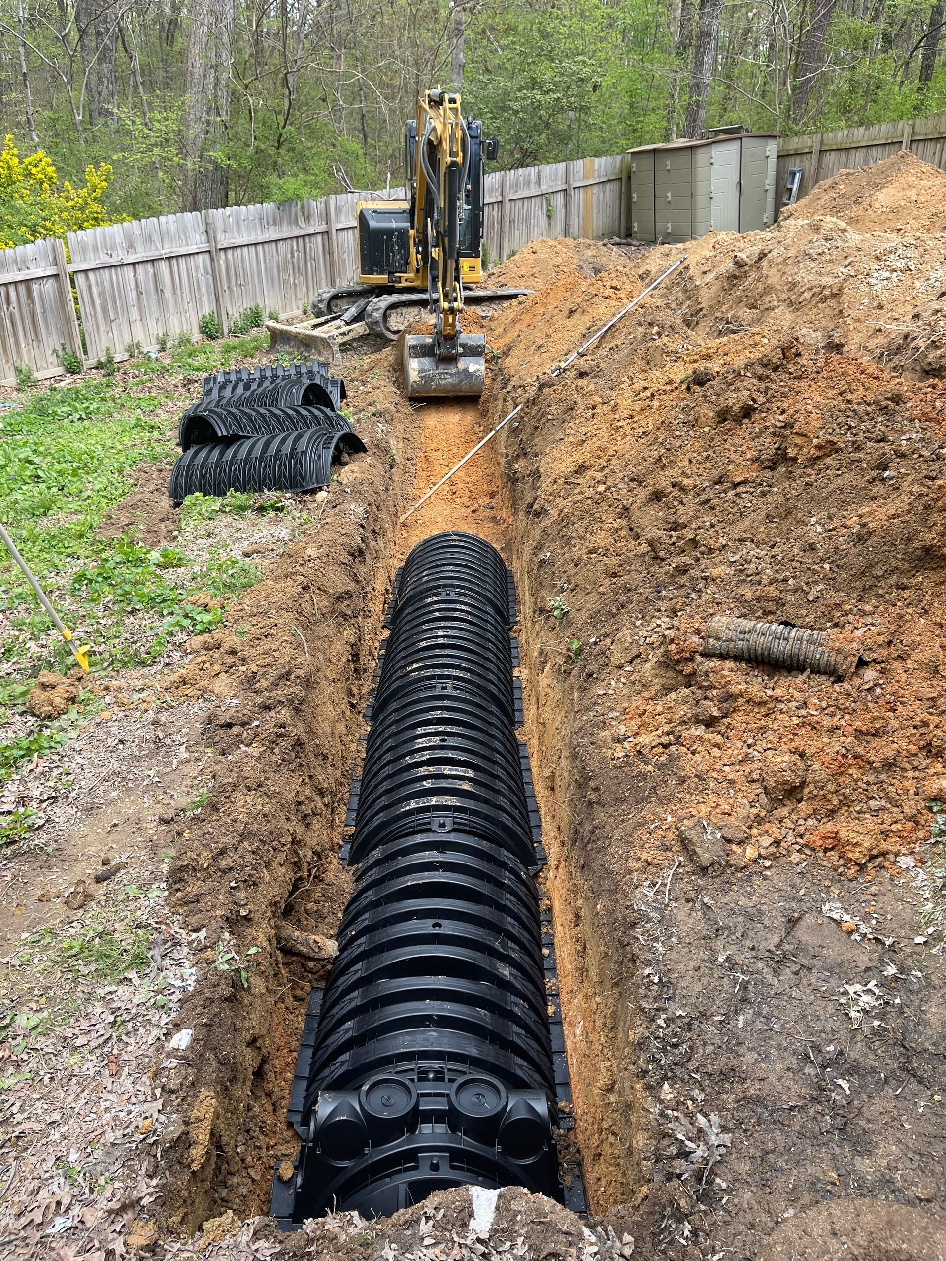 A septic tank is being installed in the dirt in a backyard.