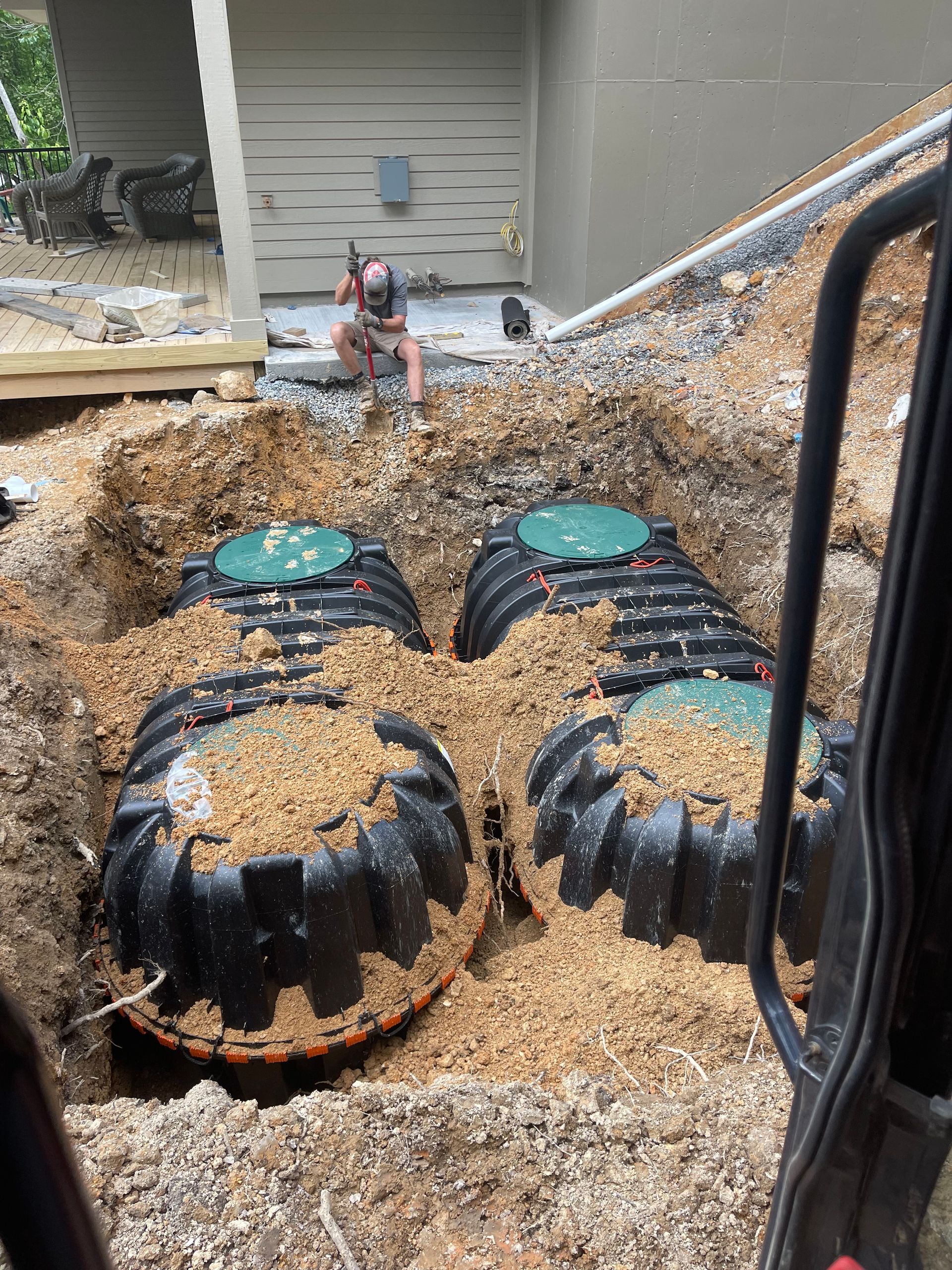 A man is sitting in the dirt next to a septic tank.