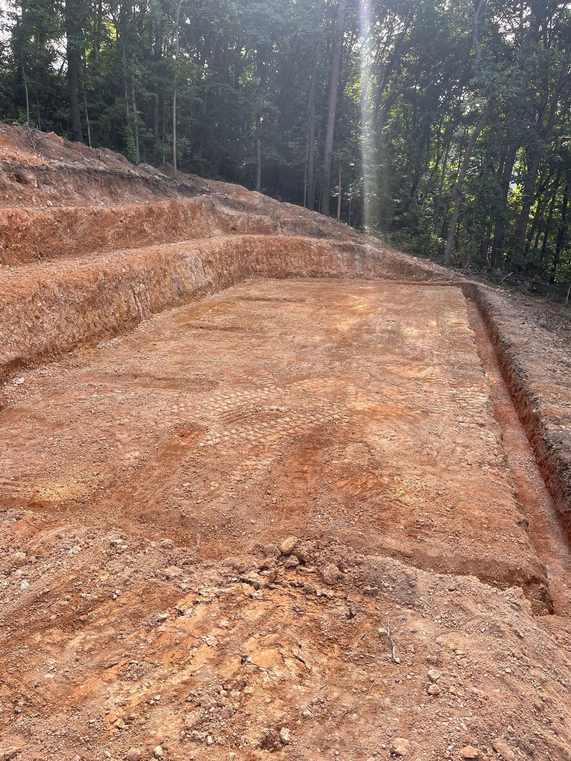 A pile of dirt and gravel on top of a hill with trees in the background.