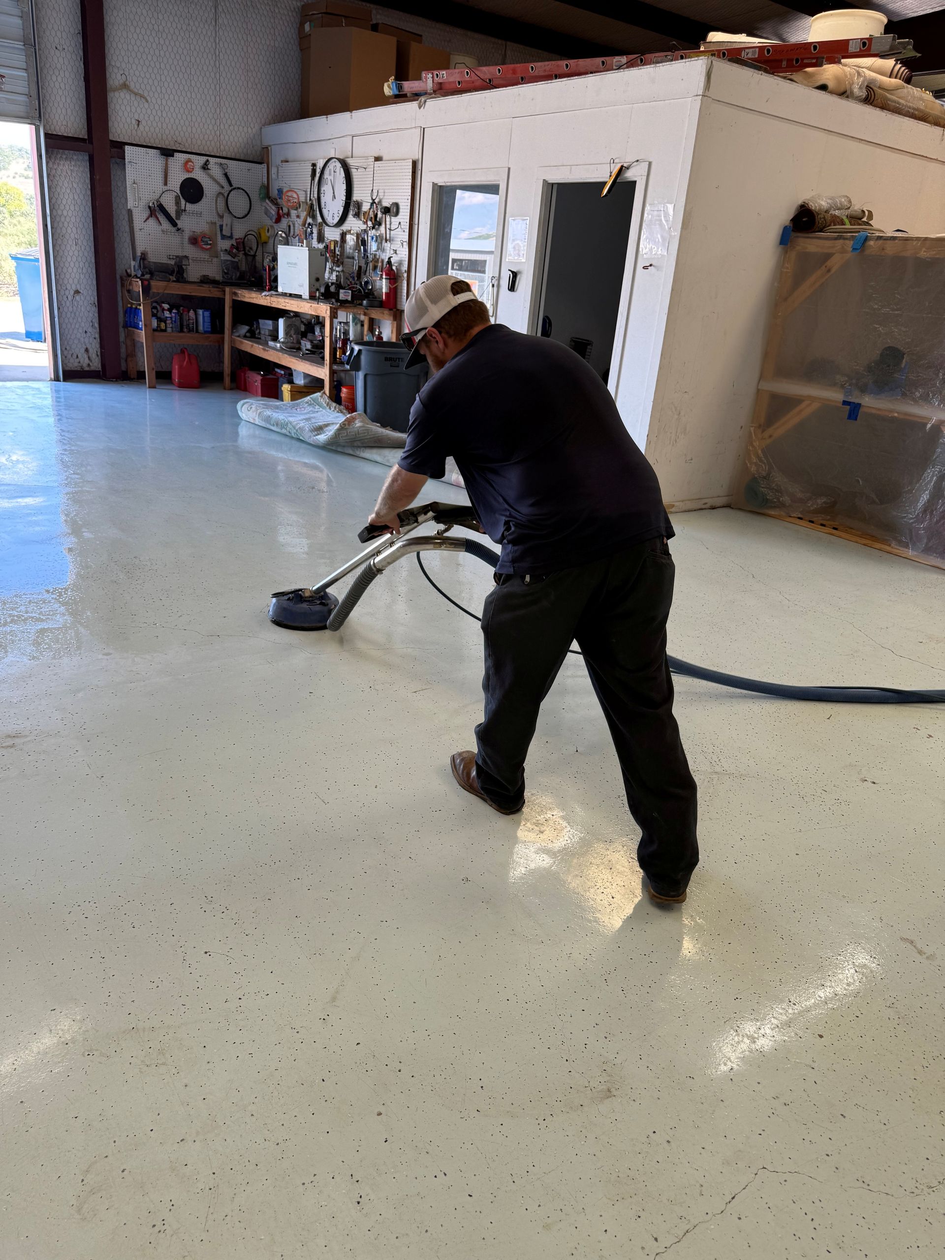 Woman in pink gloves and blue apron cleans a beige couch with a vacuum cleaner.