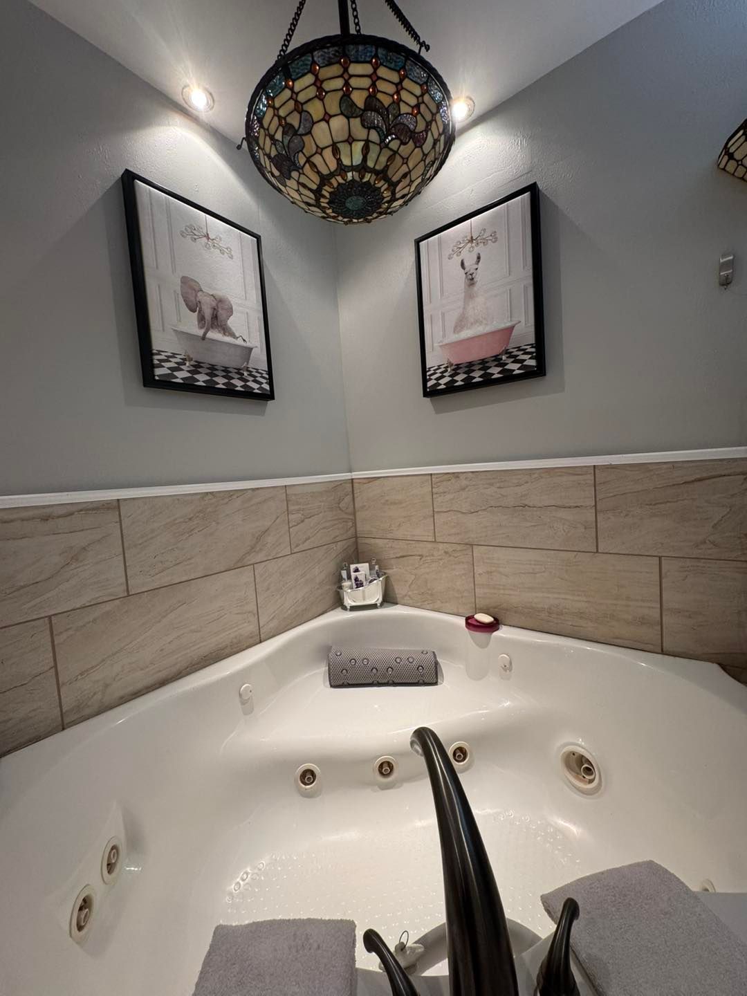 Corner jacuzzi tub with framed artwork and a decorative light fixture.